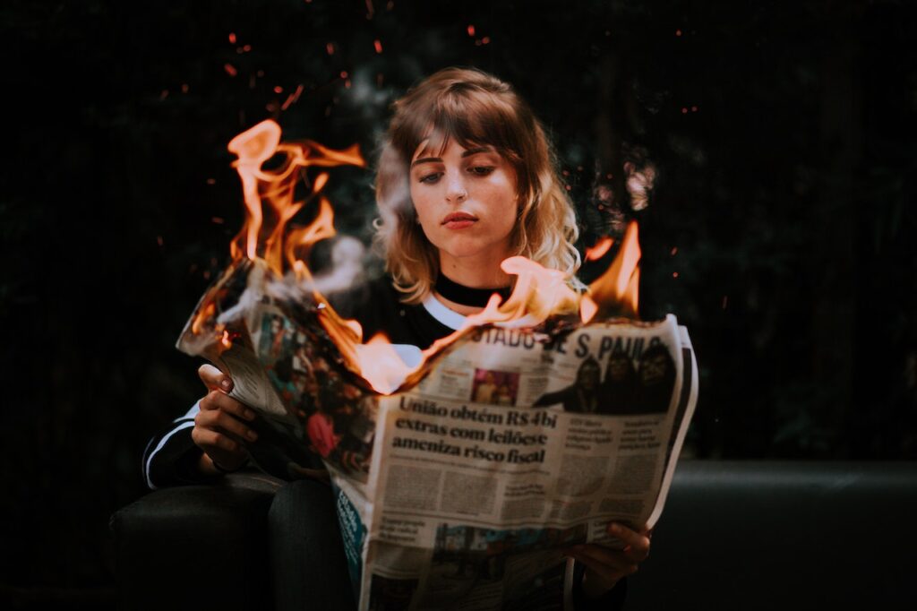 Female person holding newspaper that are on fire