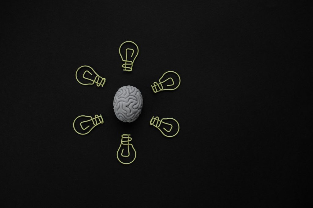 Picture of brain surrounded with cartoon light bulbs on black background