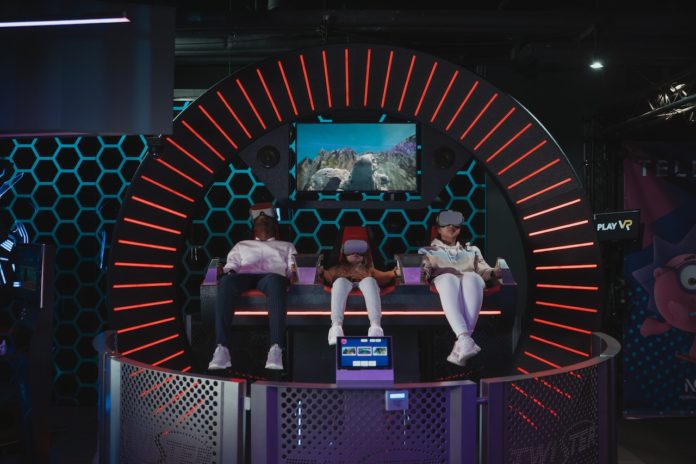Three people siting in dome playing virtual reality game with virtual reality headset