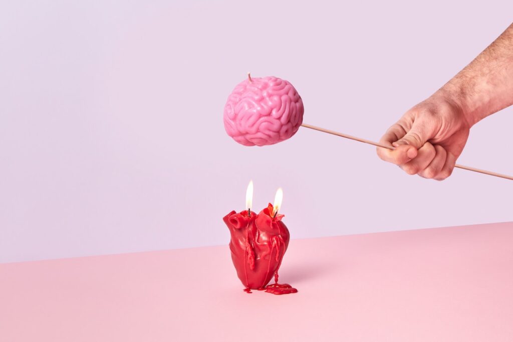 Hand holding pink brain above candle in heart shape