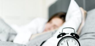 Person laying in bad with clock on night table