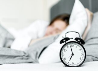 Person laying in bad with clock on night table