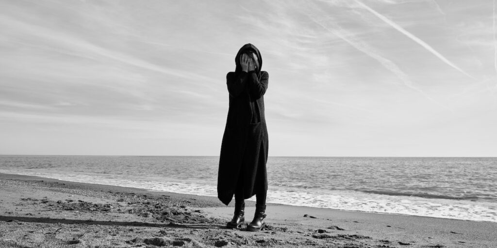 Person in black clothes standing on the beach