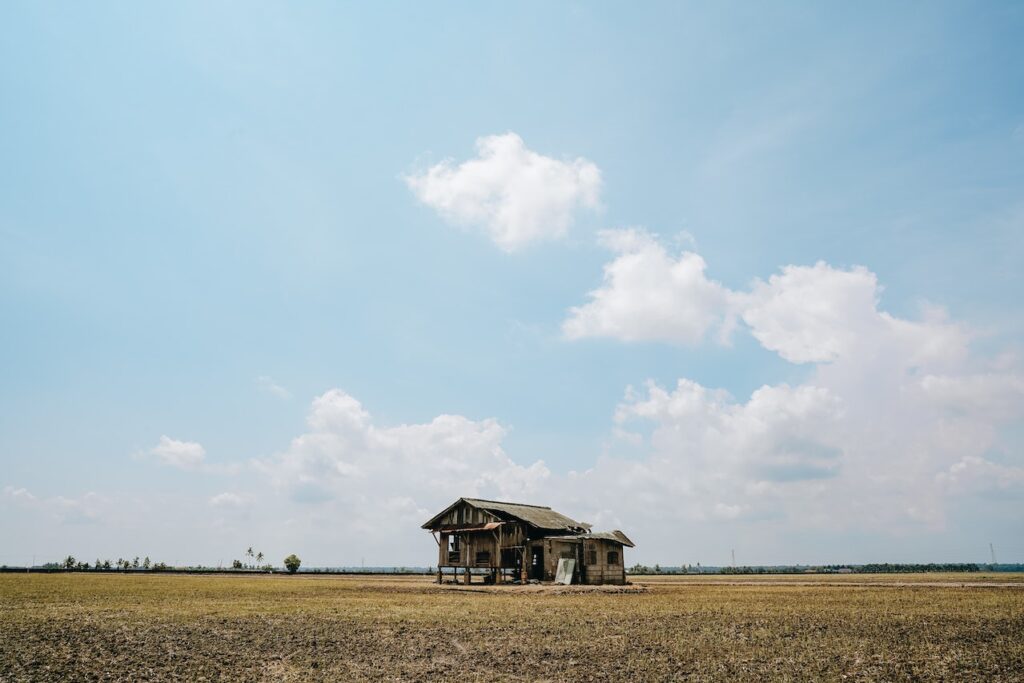 Abandoned wooden house in field with blue sky