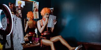 Bizarre weird strange woman applying black lipstick in dark room