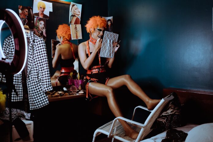 Bizarre weird strange woman applying black lipstick in dark room