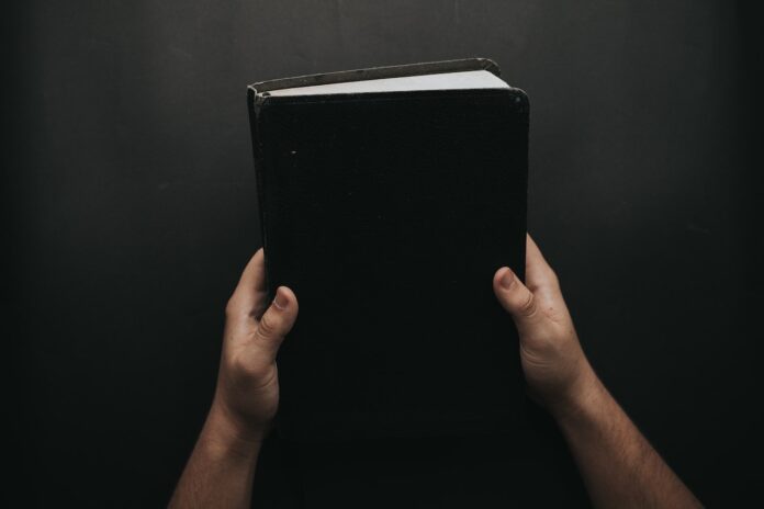 Black book the bible person holding in his hands