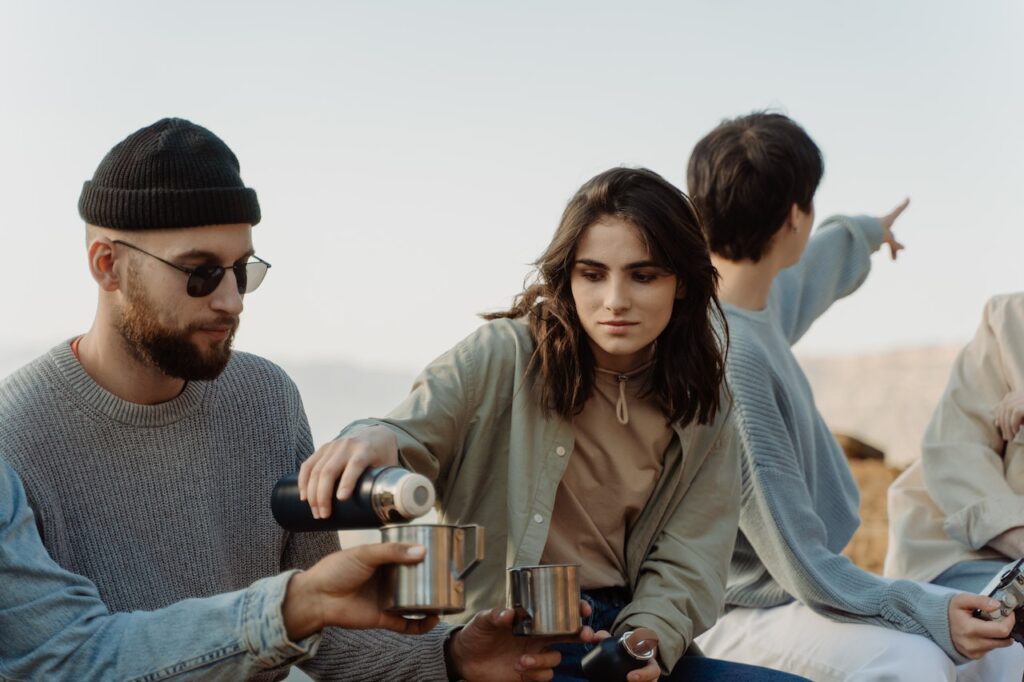 Thermos flask and people poring hot coffee 