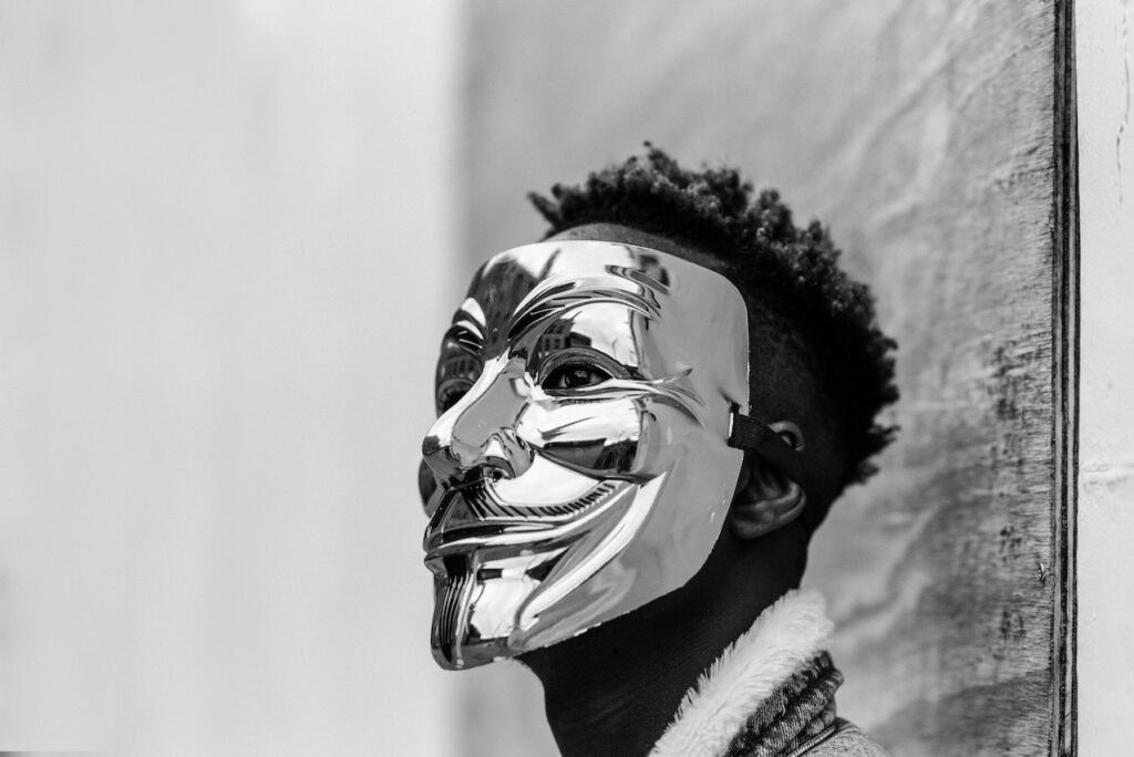 Black activist wearing Anonymous mask as sign of protest.